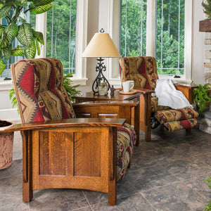 Two oak paneled Mission recliners in southwest print fabric flanking a lamp table in a sunroom with tile floor
