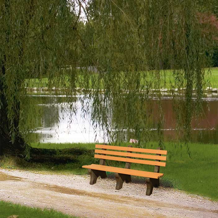 Cedar poly park bench with brown legs sitting on a gravel path under a willow tree beside a pond