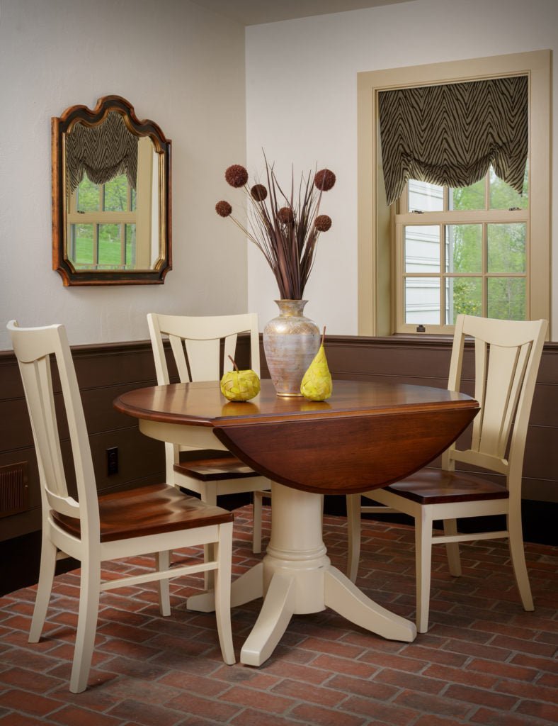 Round drop leaf pedestal table with a cherry top and cream painted base with three matching dining chairs