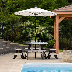 Weatherwood and black 48 inch round poly picnic table with four attached benches under a white umbrella by a pool