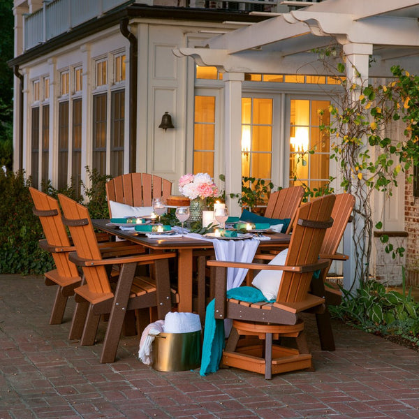 Cedar and brown poly 72 inch bistro patio dining table with six fan back swivel chairs set for dinner at dusk