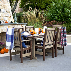 Weatherwood and brown poly 72 inch English Garden dining table with six chairs set for fall dinner by a stone fireplace
