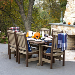Weatherwood and brown poly English Garden dining table with six slat back chairs set with pumpkins beside a stone fireplace