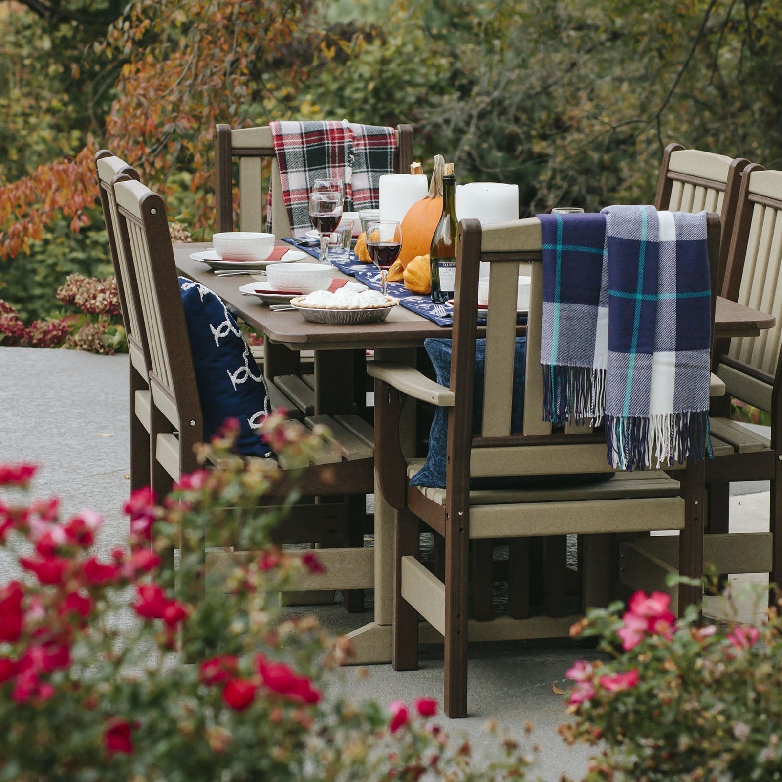 Six weatherwood and brown poly English Garden chairs around a rectangular poly patio table with autumn table setting