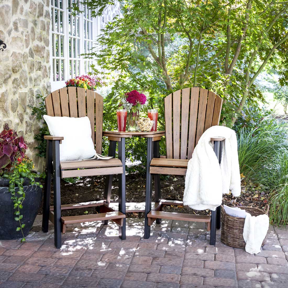 Two blue and gray poly bar height Adirondack chairs joined by a center table with navy umbrella beside a pool