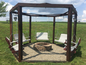 Poly porch swings hanging around a backyard fire pit under a stained wood pergola with hanging lanterns