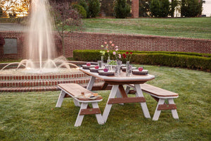 Cedar and white bordered poly garden table with two benches set with glassware beside a spraying fountain