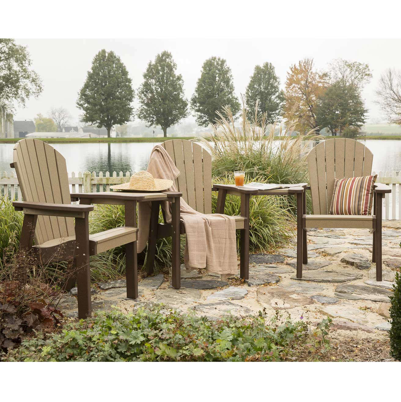 Three seat poly patio settee with two weatherwood Adirondack chairs and a brown connector table on a stone patio