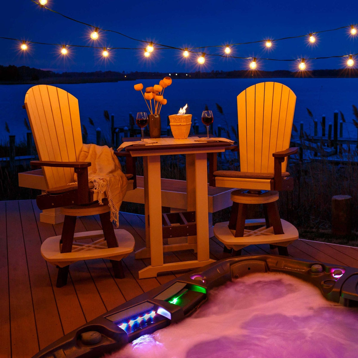 Three piece patio set of two swivel Adirondack bar chairs and a pub table lit by string lights beside a hot tub