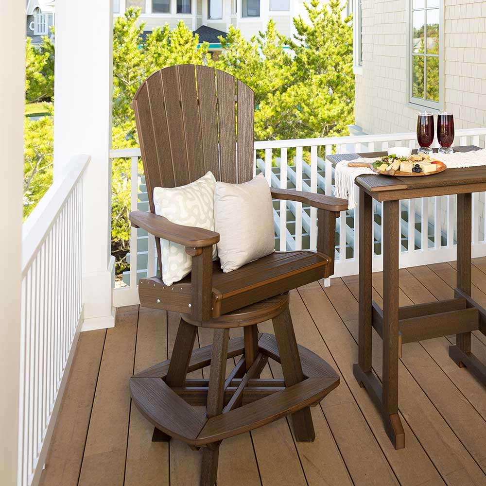 Brown poly swivel counter chair with fan back, white pillows and a curved swivel base on a covered porch