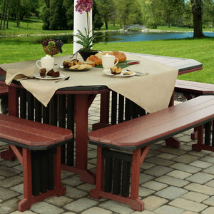 Cherrywood and black poly patio dining table dressed with a linen cloth and pastries, flanked by matching benches by a pond