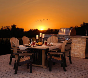 Cedar and black poly patio dining table with four arm chairs set for dinner by an outdoor grill island at sunset