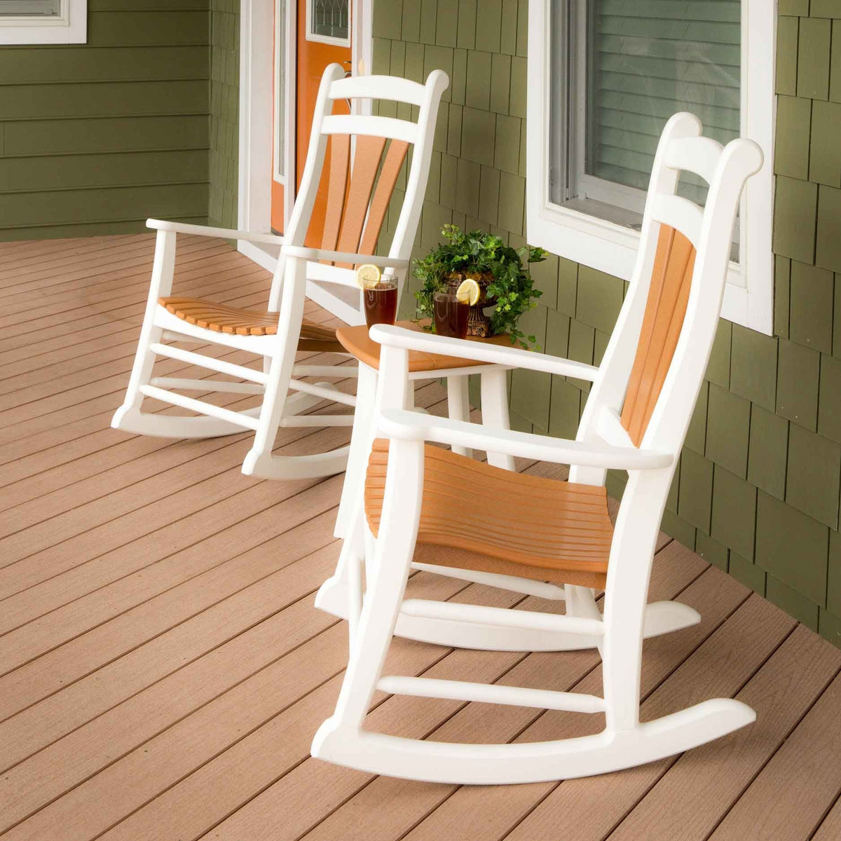 White poly rocking chairs with cedar contoured seats and back slats beside a table with iced tea on a deck