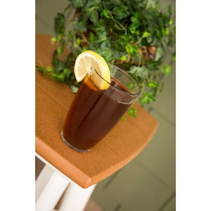 Glass of iced tea with a lemon slice on a cedar poly side table beside an ivy plant on a porch