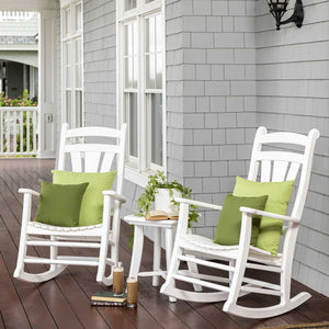 Pair of white poly porch rockers with green pillows and a small side table on a shingled front porch