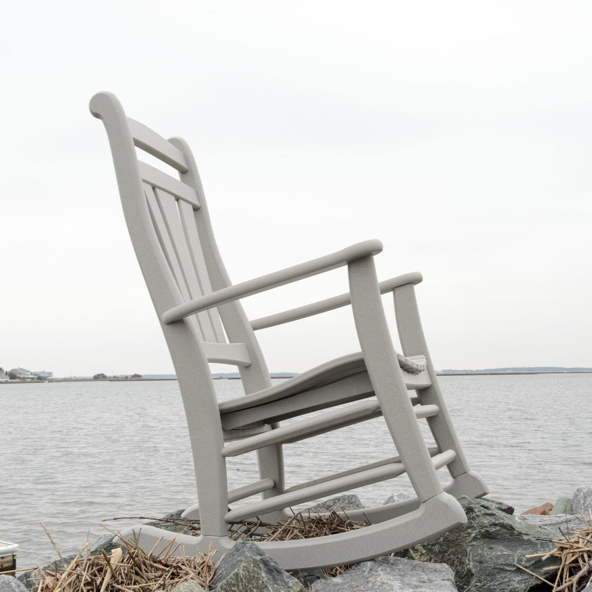 Gray poly rocker viewed from the side on rocks at the edge of a wide bay under an overcast sky