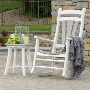 White poly rocker with a gray slat seat and matching side table holding daisies and lanterns on a patio