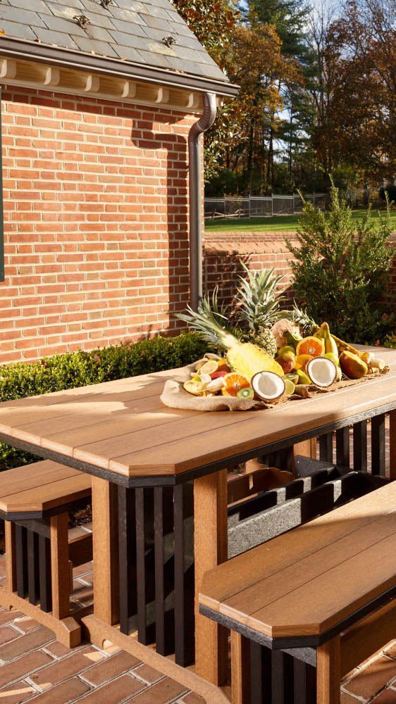 Cedar and black Mission poly table with slatted trestle legs and matching benches holding a tropical fruit display