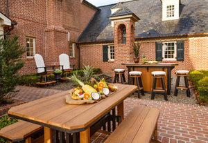 Cedar poly Mission dining table with two matching benches in a brick courtyard near an outdoor bar with stools