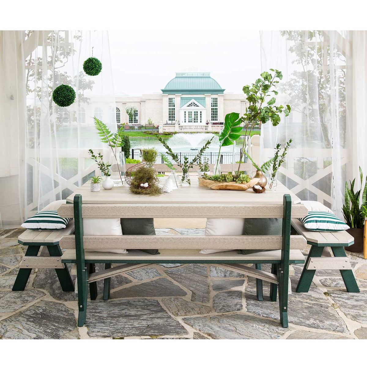 Poly garden table set with cushioned benches under sheer curtains looking out to a fountain and estate