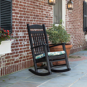 Black poly lumbar rocking chair with slatted back, floral cushion and curved rockers on a brick porch