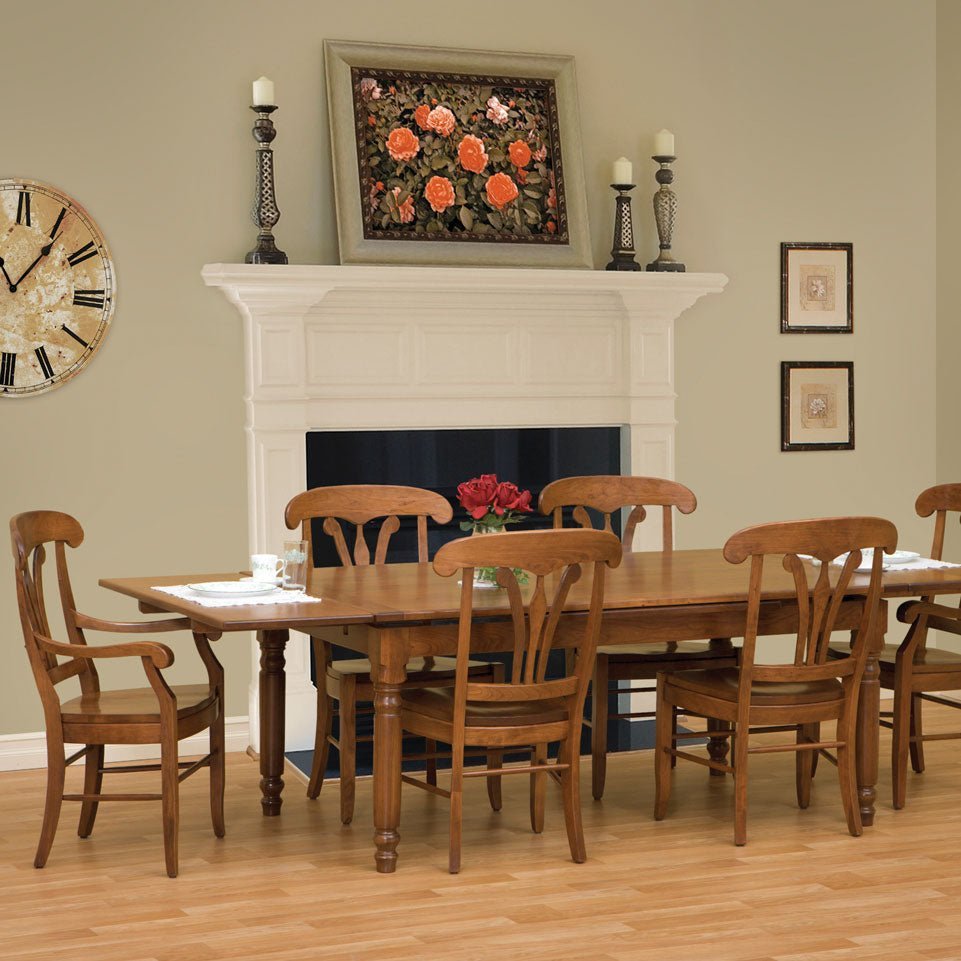 Cherry draw leaf table extended with six chairs in a dining room with a white fireplace mantel and wall clock