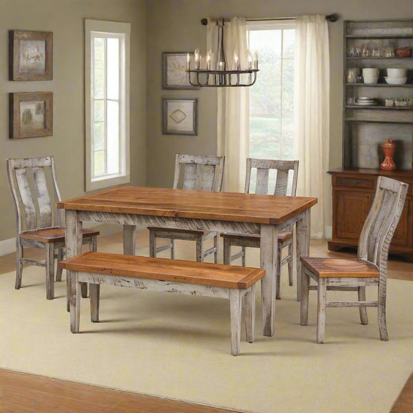 Whitewashed farm dining set with a honey stained top, four curved slat back chairs and a bench under a chandelier