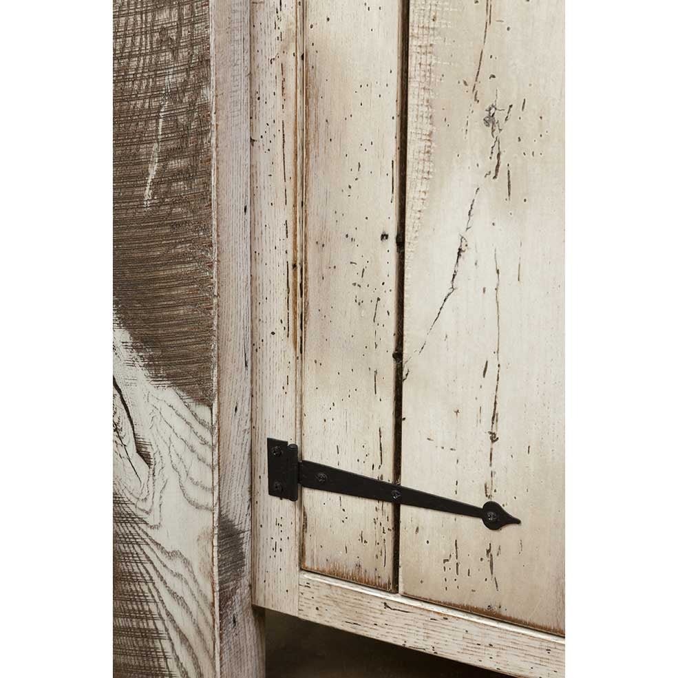 Close up of an iron strap hinge on the whitewashed plank door beside the island's rough sawn corner post