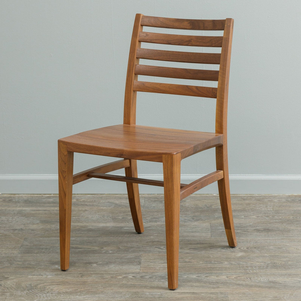 Walnut mid century dining chair with a five slat ladder back, scooped solid seat and splayed tapered legs