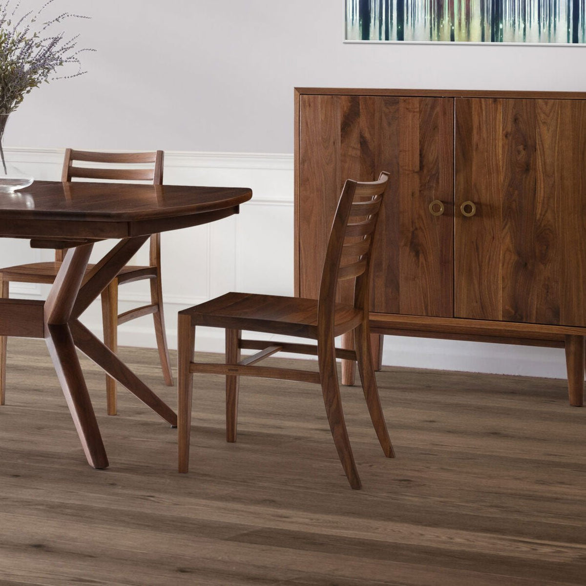 Walnut ladder back dining chairs at a table with splayed legs beside a matching two door credenza