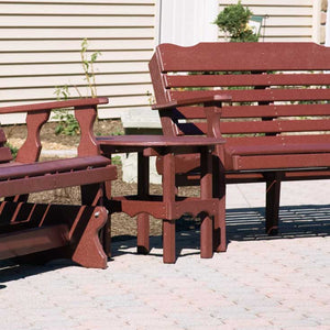 Cherry red poly round side table between a glider and a slat back bench on a paver patio