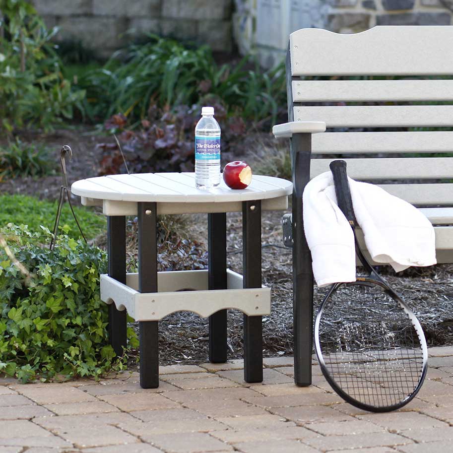 Driftwood gray and black poly round side table with water bottle and apple, beside a matching garden bench
