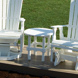 White poly round side table set between two white gliders on a deck overlooking a lawn