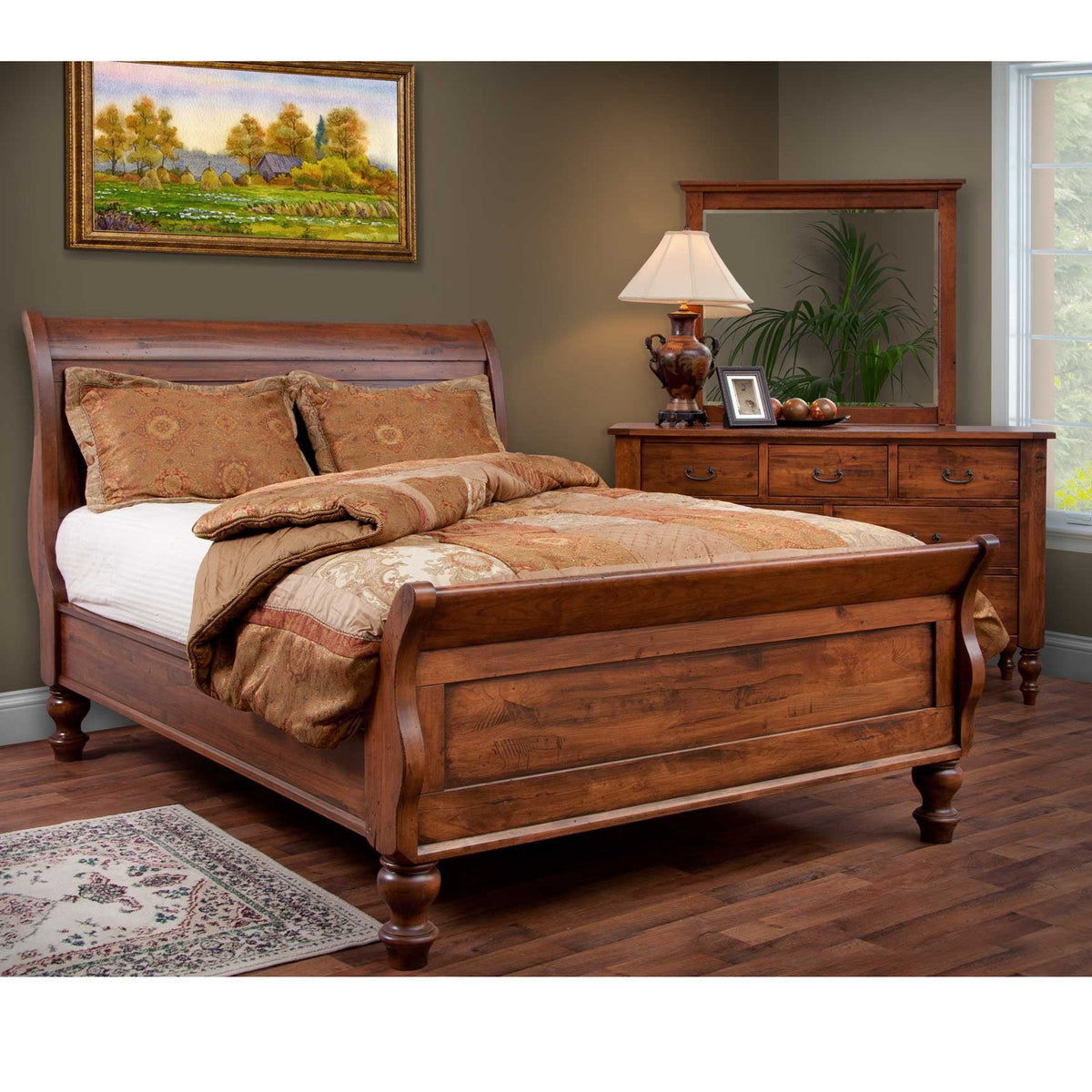 Bedside view of a cherry sleigh bed with tapestry pillows and a three drawer nightstand with bail pulls
