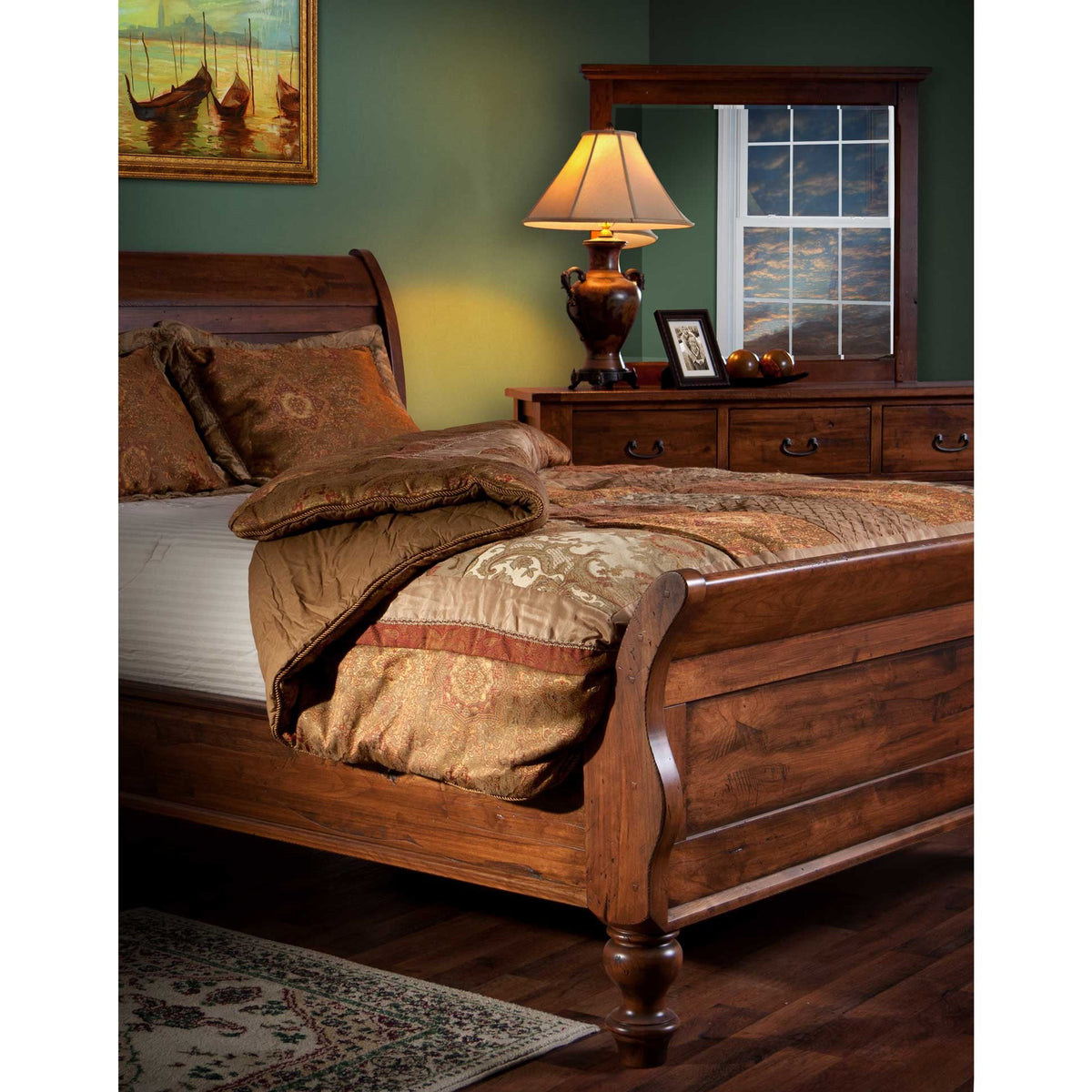 Sleigh bed in rustic cherry beside a matching dresser and mirror in a green bedroom with lamp light
