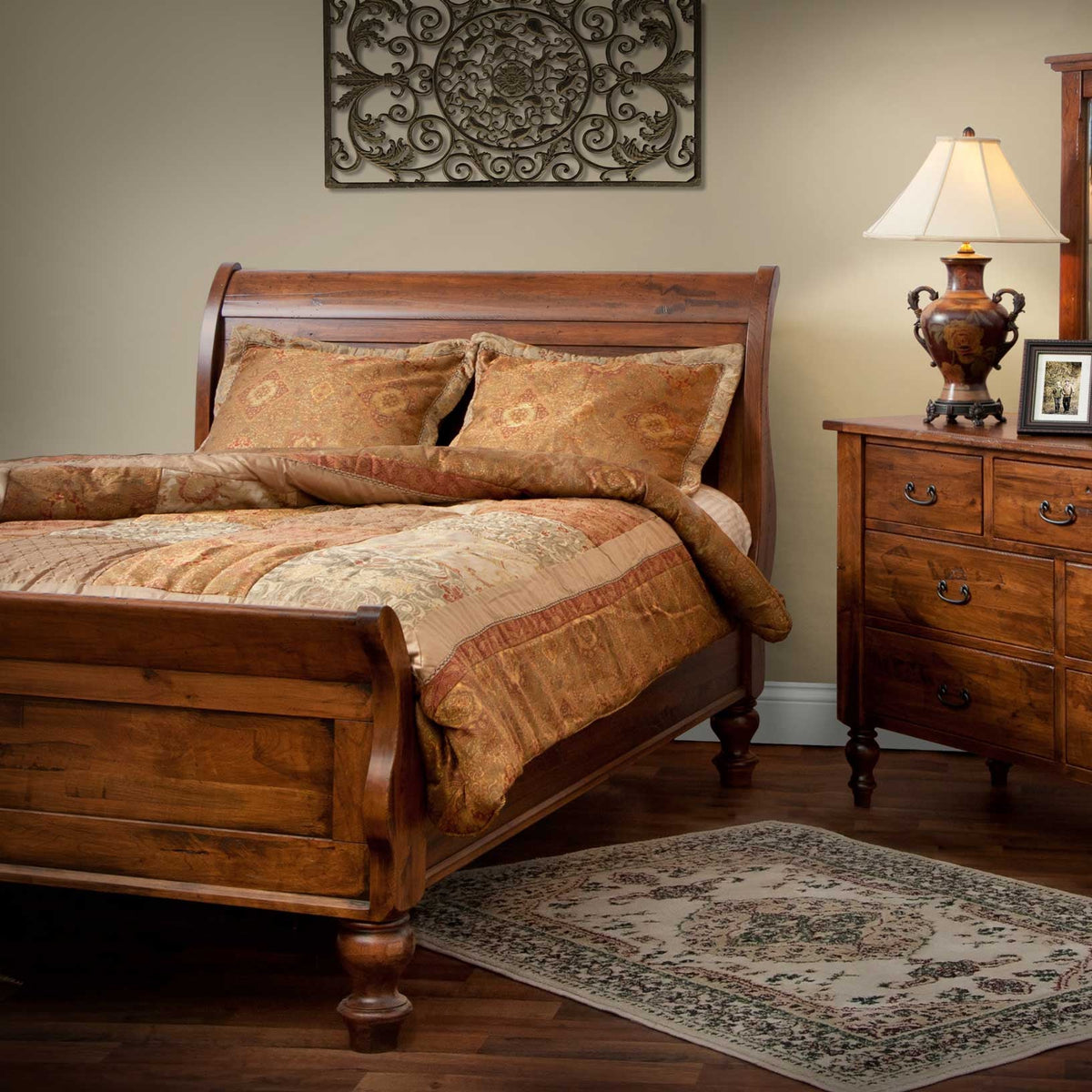 Cherry sleigh bed styled in a warm bedroom with tapestry bedding, nightstand, lamp and scrolled wall art
