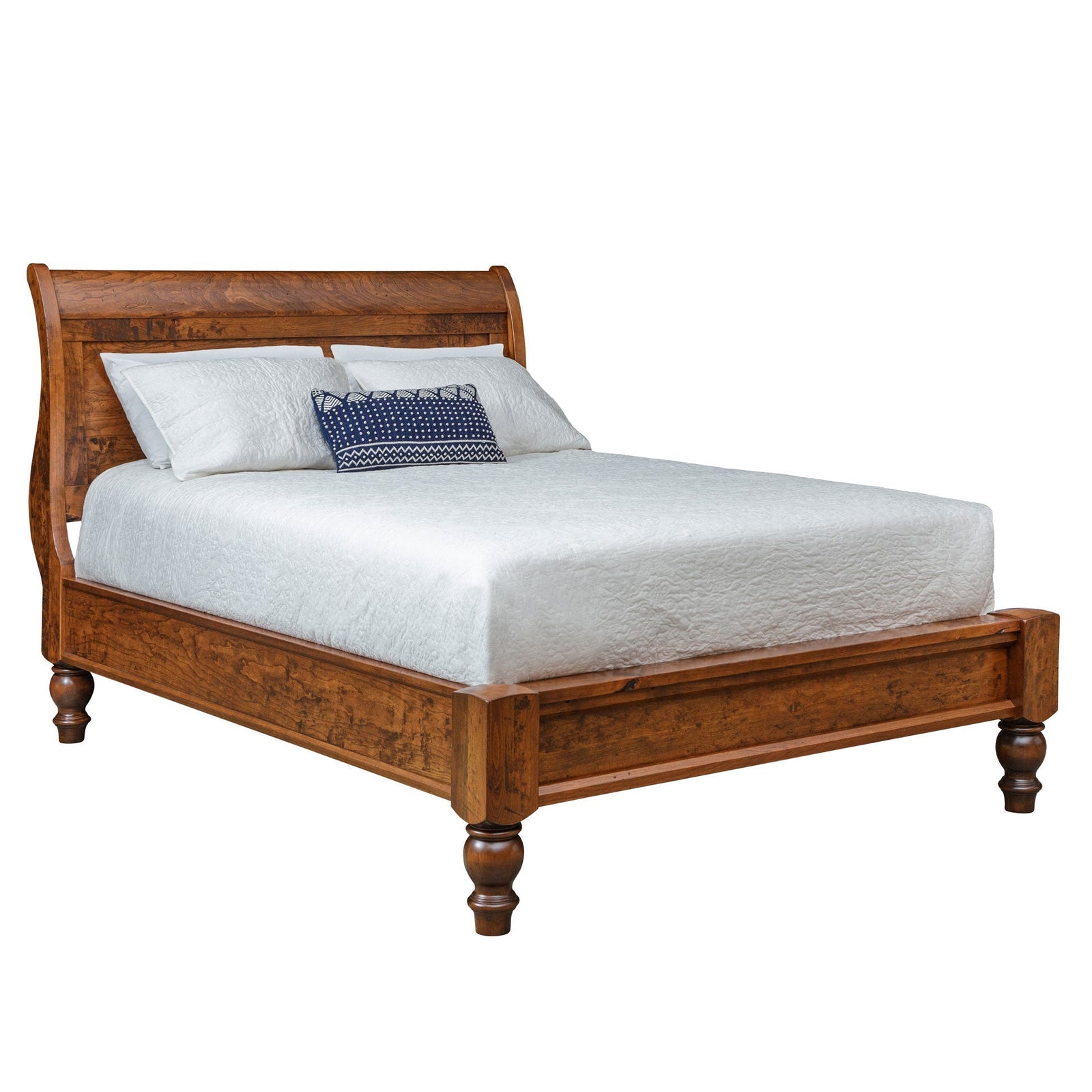 Cherry sleigh bed with low footboard and turned feet styled with white bedding, nightstand and tall chest