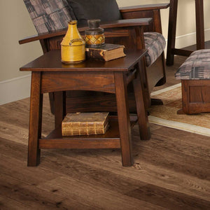 Dark brown Santa Fe end table with drawer and lower shelf holding pottery and antique books on wood flooring