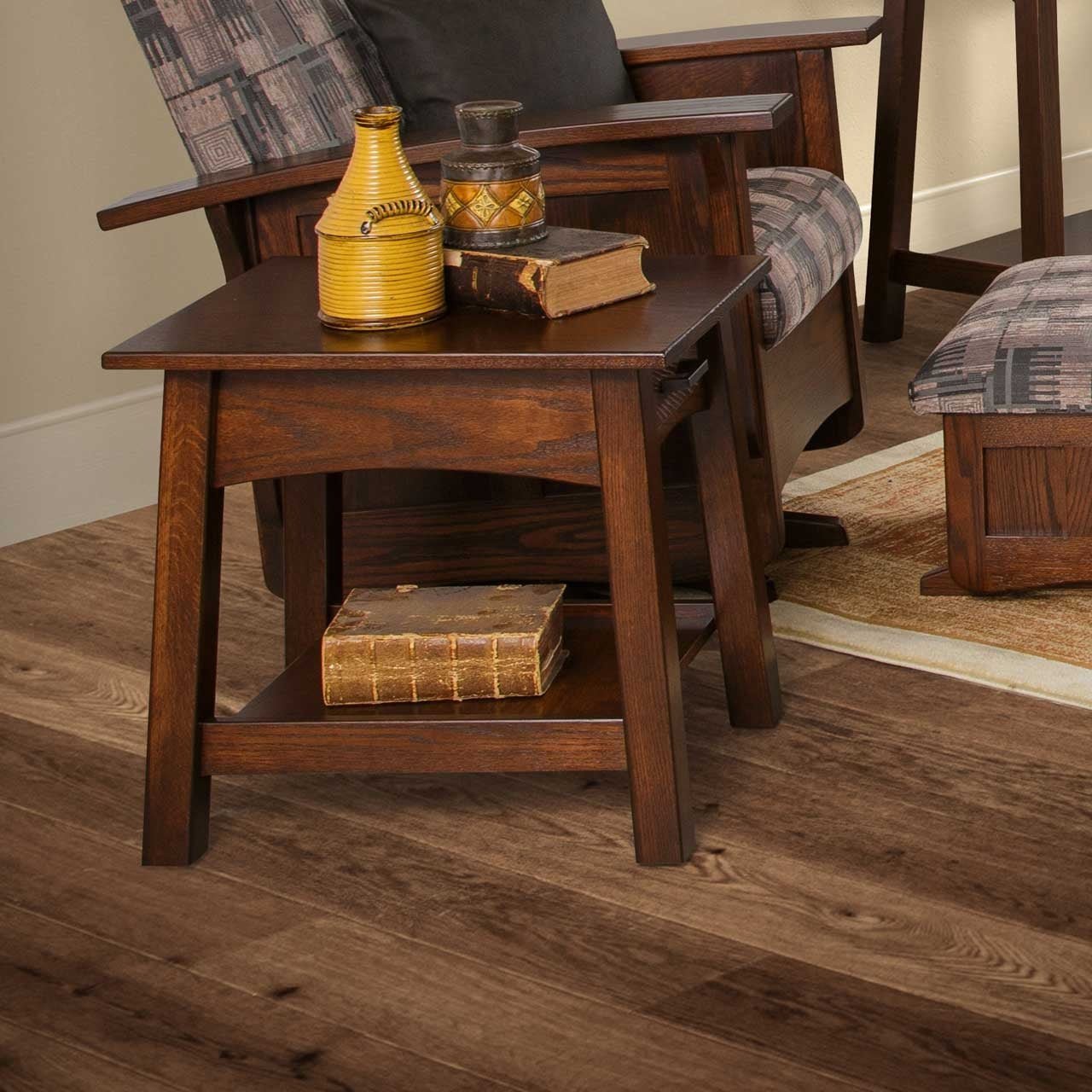 Dark brown Santa Fe end table with drawer and lower shelf holding pottery and antique books on wood flooring
