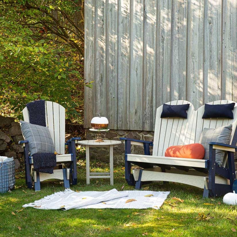 Backyard seating scene with matching birch and navy poly Adirondack glider chair, double glider bench and round side table on grass