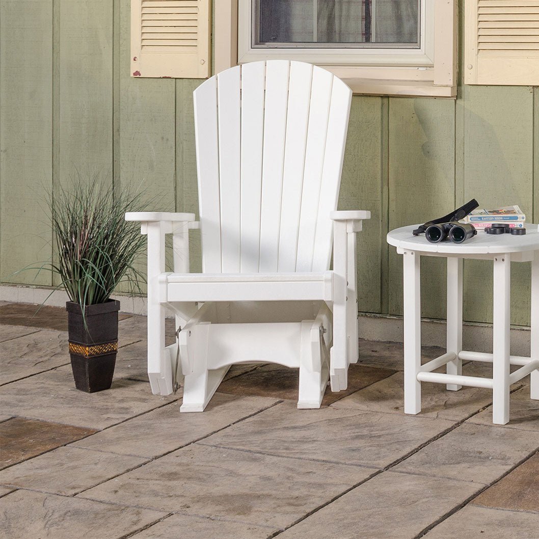 White poly Adirondack glider chair with fan back and wide arms on a stamped patio beside a round side table