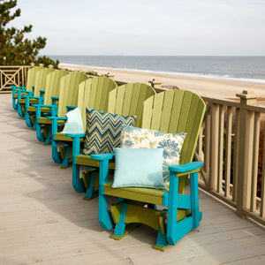 Row of lime green and aruba blue Adirondack glider chairs with patterned pillows lining an oceanfront boardwalk deck