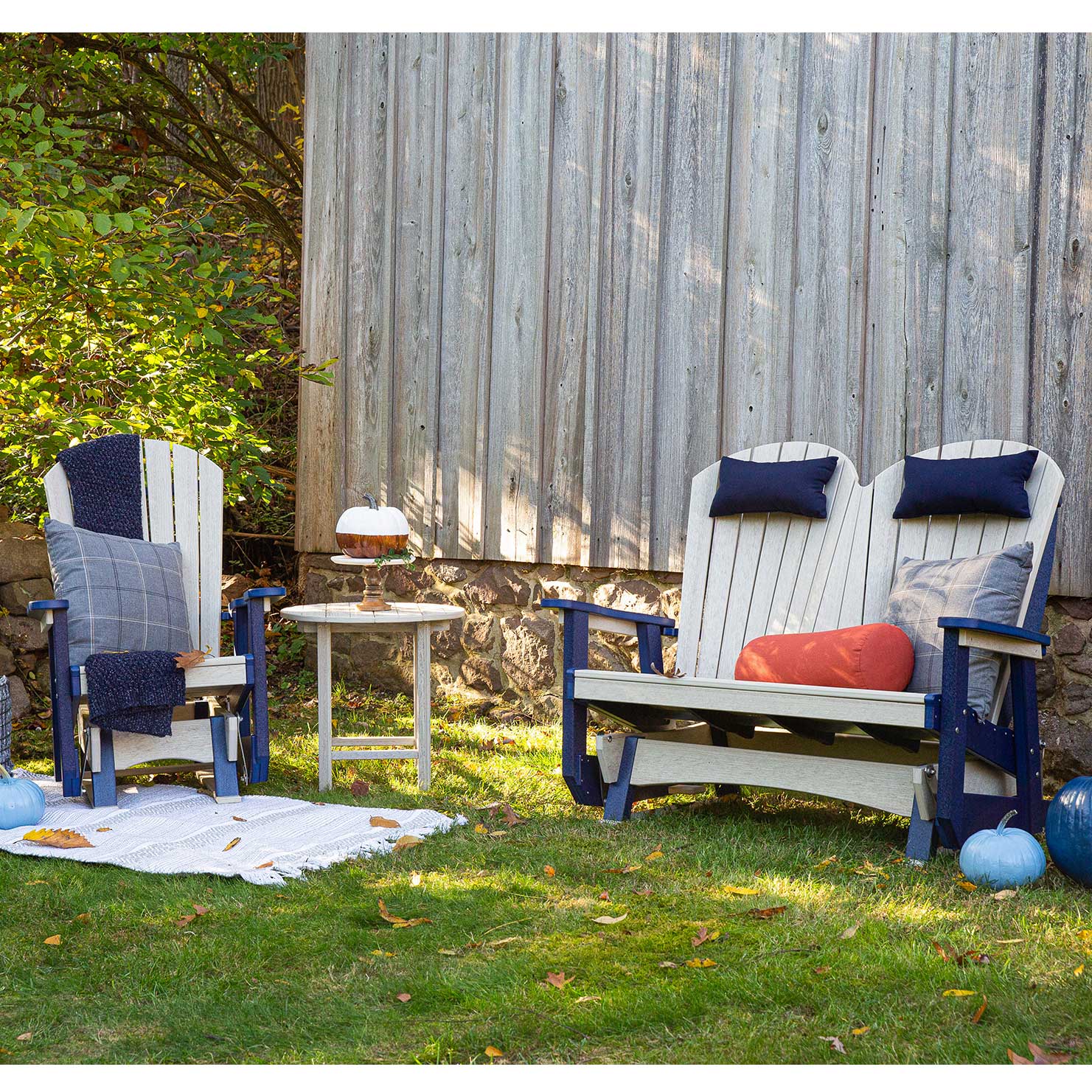 White poly Adirondack glider chair and two-seat glider bench with a round side table on a stamped concrete patio
