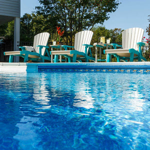 White and aruba blue poly lounge chairs beside a bright blue pool with drinks on round tables in the background