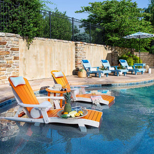Orange and white poly chaise lounges with a round table of fruit set in the shallow ledge of a stone pool