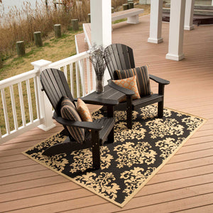 Two black poly Adirondack chairs joined by a center table attachment with striped pillows on a waterfront porch