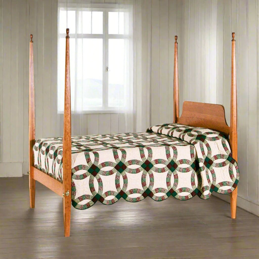 Cherry four post pencil bed with tapered posts and a wedding ring quilt in a whitewashed plank room