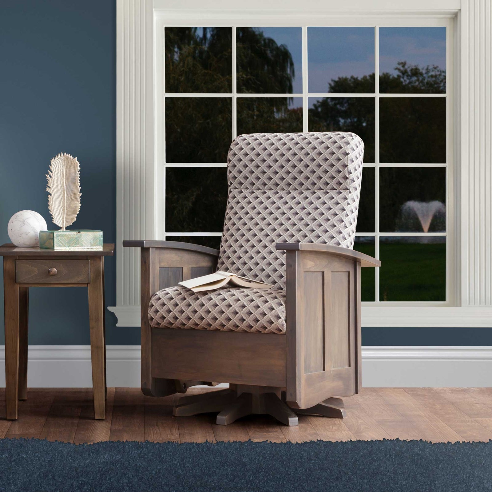 Gray stained Shaker swivel glider with cream diamond quilted cushions and paneled sides beside a lamp table