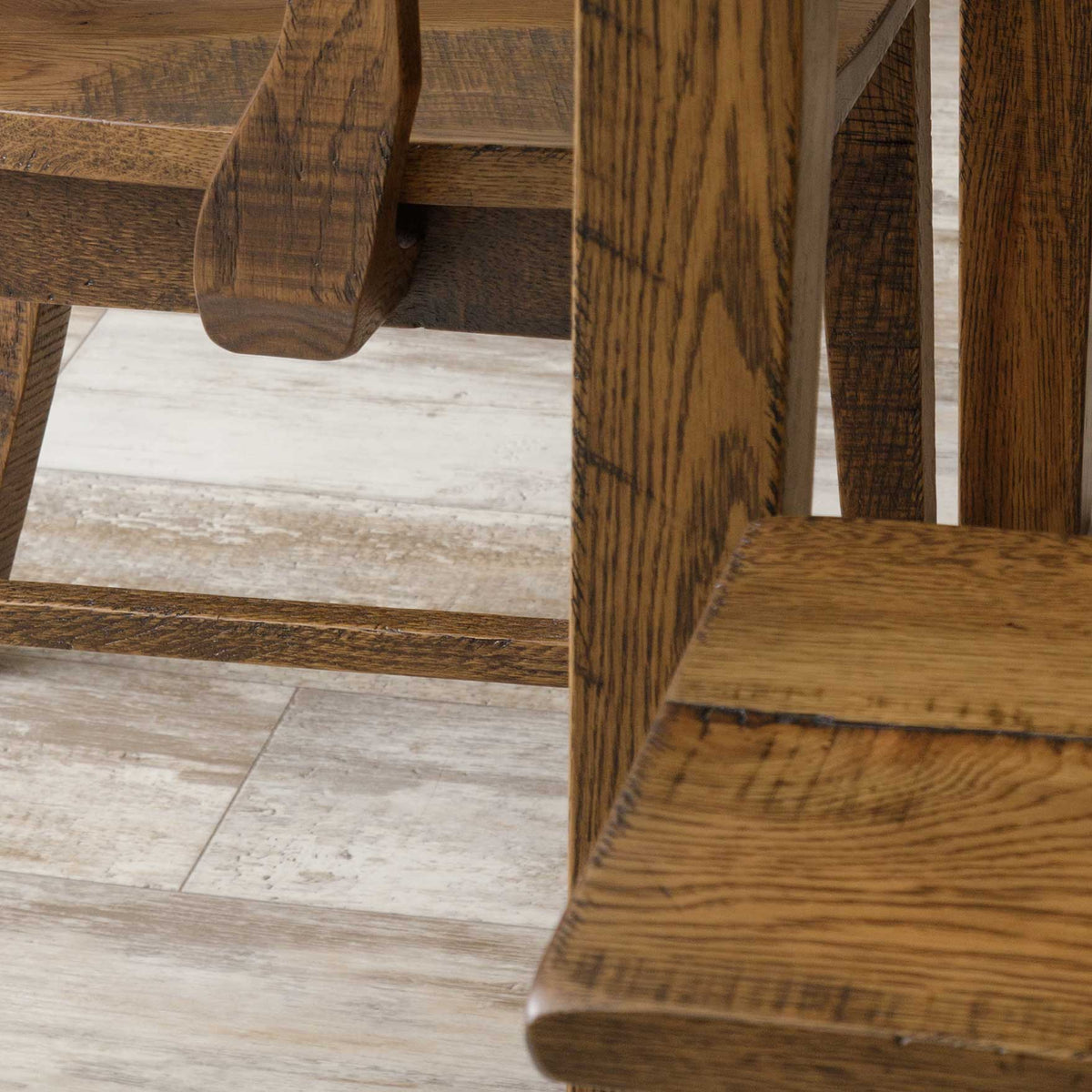 Low angle detail of rustic oak dining chair and bench legs with cross rungs, showing the distressed oak grain