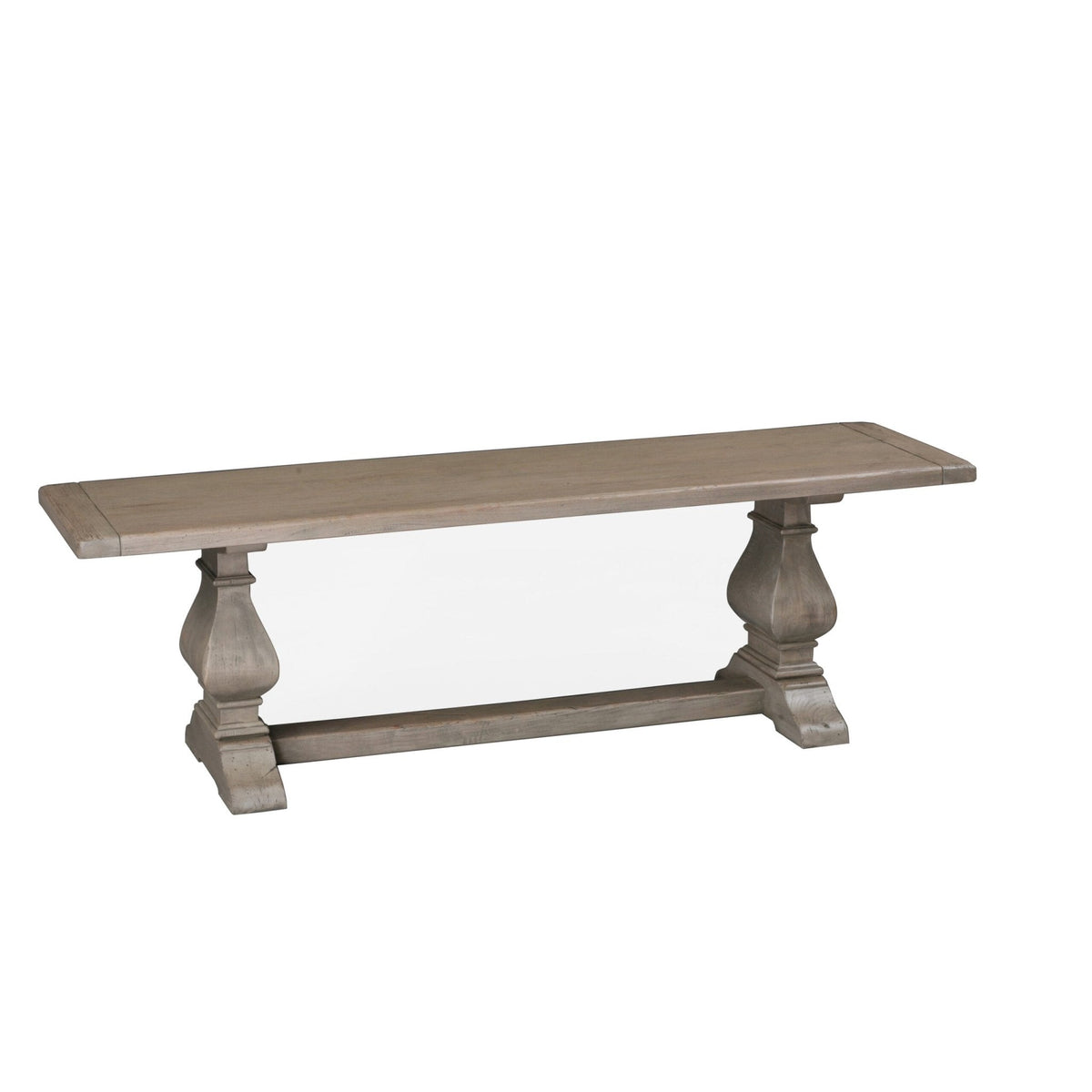 Weathered gray dining bench with a plank seat supported by two urn shaped pedestals and a trestle stretcher on a white background